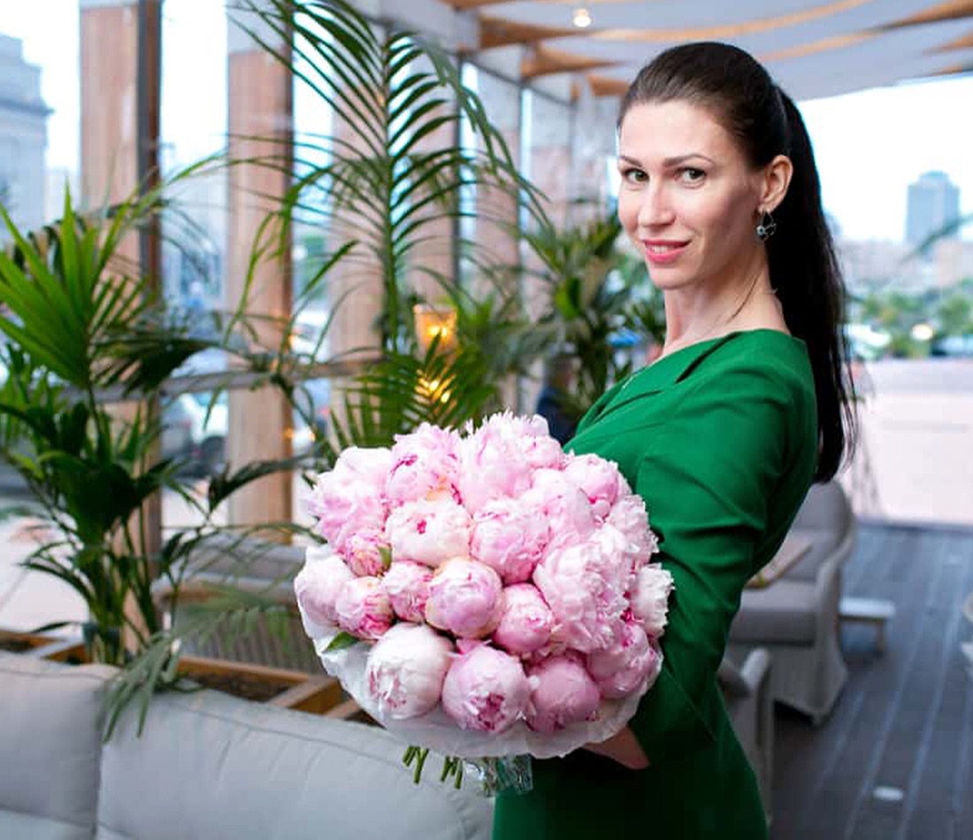 Olga holding a large bouquet of pink peonies