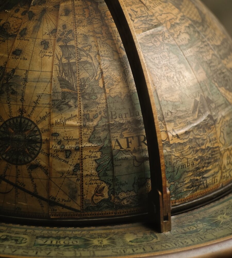 A vintage world map and compass beneath a starlit sky, evoking the astrology of moving